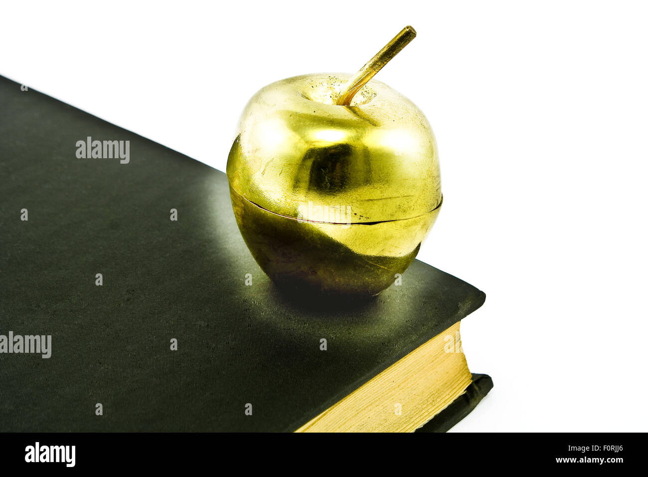 Golden Apple sul vecchio libro nero isolato su bianco Foto Stock