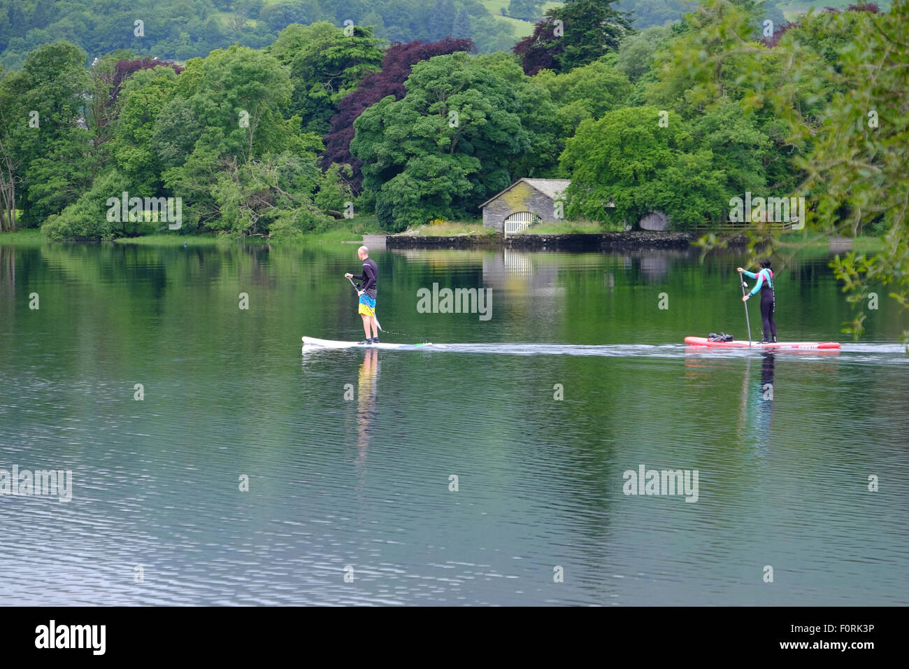 Due persone sullo stand up paddleboards su Conniston acqua nel distretto del lago, REGNO UNITO Foto Stock