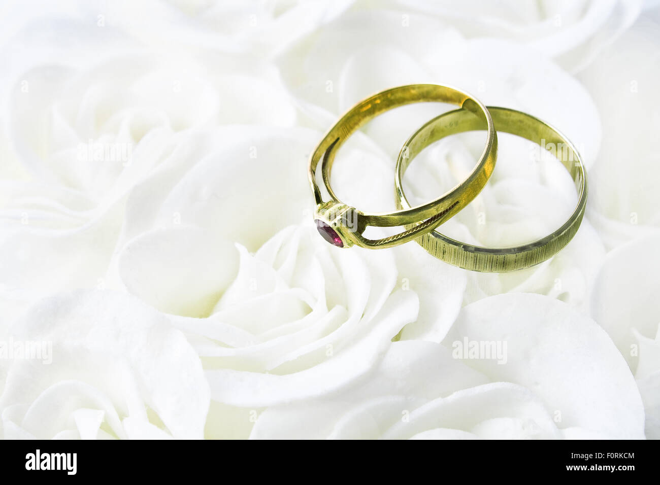 Due anelli di nozze su rose bianche Foto Stock