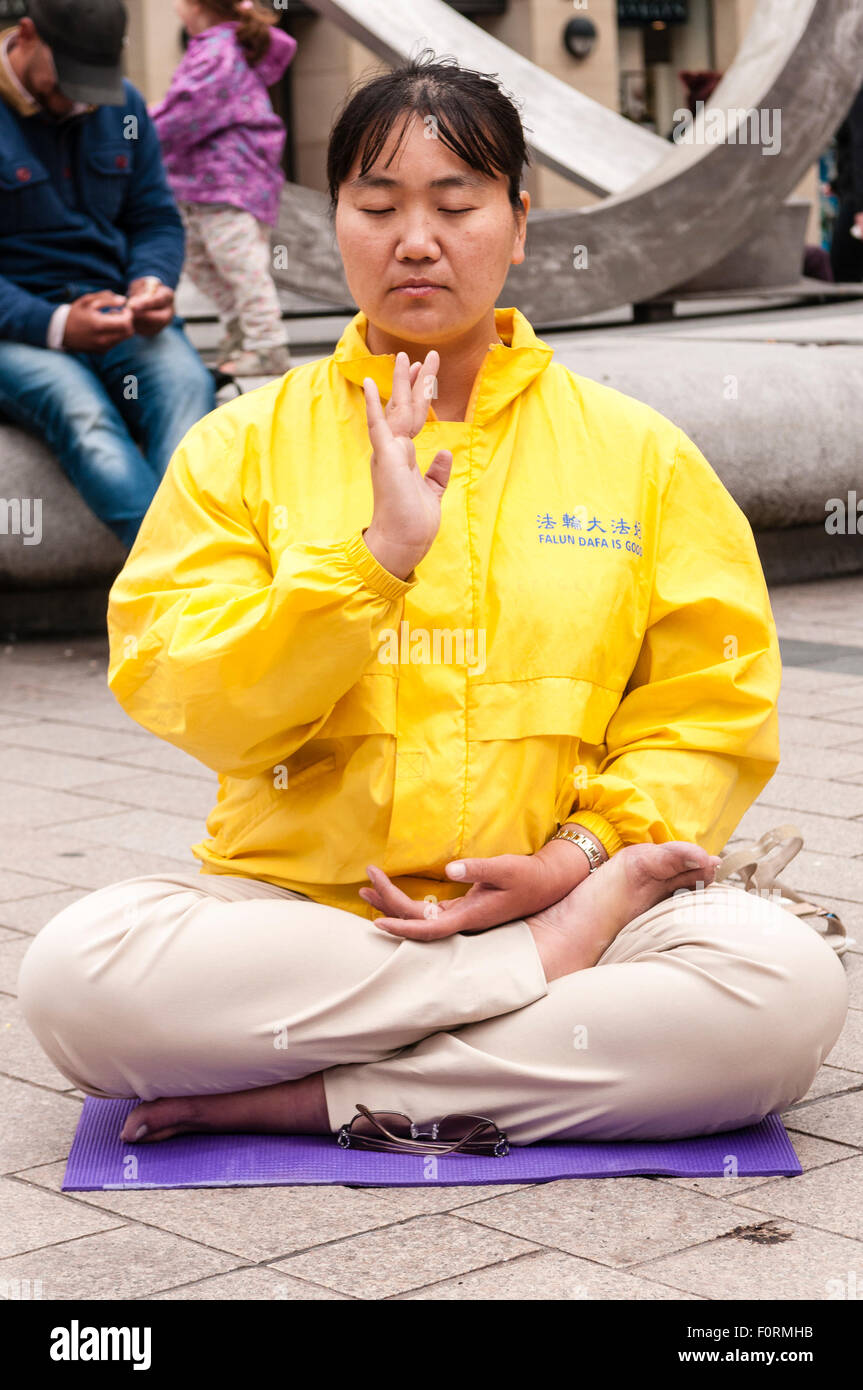 Una donna cinese practice Falun Gong (Dafa) in un trafficato centro cittadino Foto Stock