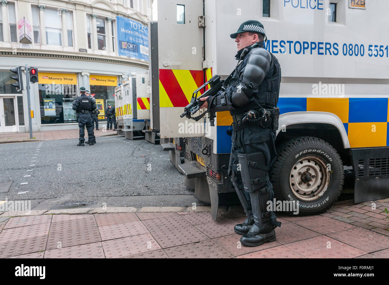 PSNI armati funzionario di polizia detiene una Heckler & Koch G36C macchina automatica pistola su una strada a Belfast come auto blindate blocco road Foto Stock