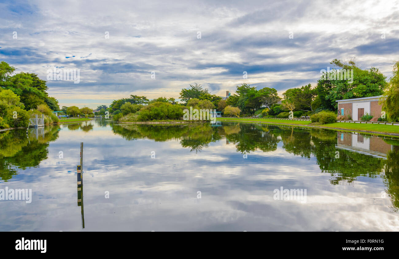 Il lago con il cielo e gli alberi che riflettono in acqua a Mewsbrook Park, Littlehampton, West Sussex, in Inghilterra, Regno Unito. Foto Stock