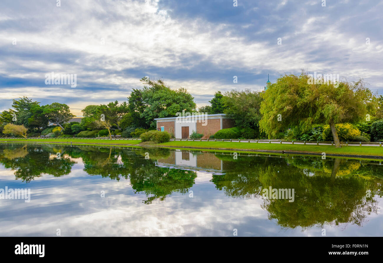 Il lago con il cielo e gli alberi che riflettono in acqua a Mewsbrook Park, Littlehampton, West Sussex, in Inghilterra, Regno Unito. Foto Stock