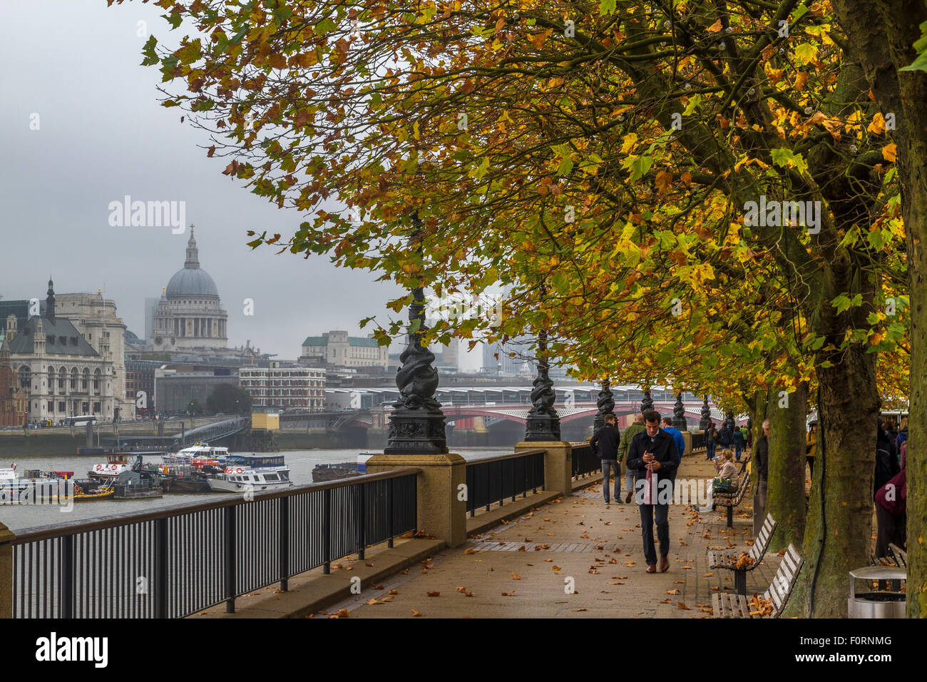 La gente camminare lungo il fiume Tamigi sulla banca del sud durante l'autunno con la Cattedrale di St Paul e nella distanza , South Bank , London , REGNO UNITO Foto Stock