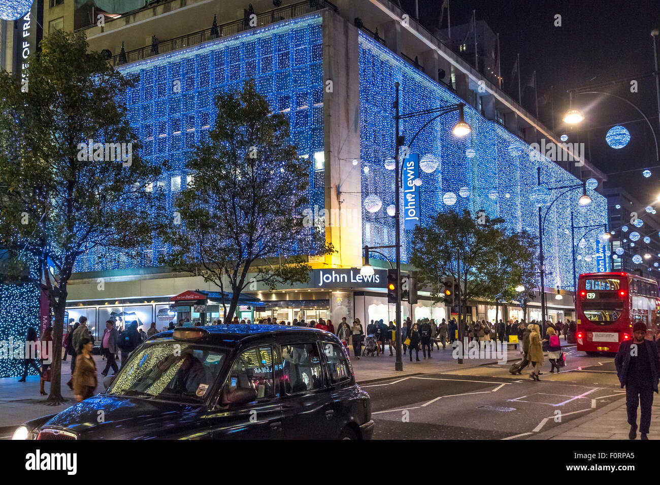 Il grande magazzino John Lewis su un'affollata Oxford St, affollato da clienti natalizi con le luci di Natale di Oxford St in mostra, Londra, Regno Unito Foto Stock