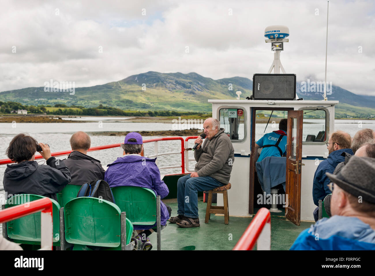 Una guida che parla nel microfono su un giro in barca lungo la Baia di Clew vicino a Westport, County Mayo, Irlanda Foto Stock