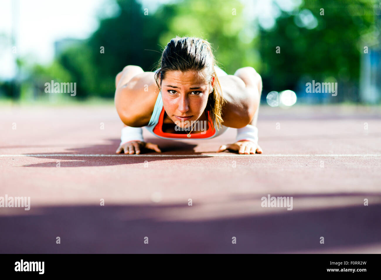 Focalizzato giovane bella donna facendo push-up all'aperto in una calda giornata estiva Foto Stock