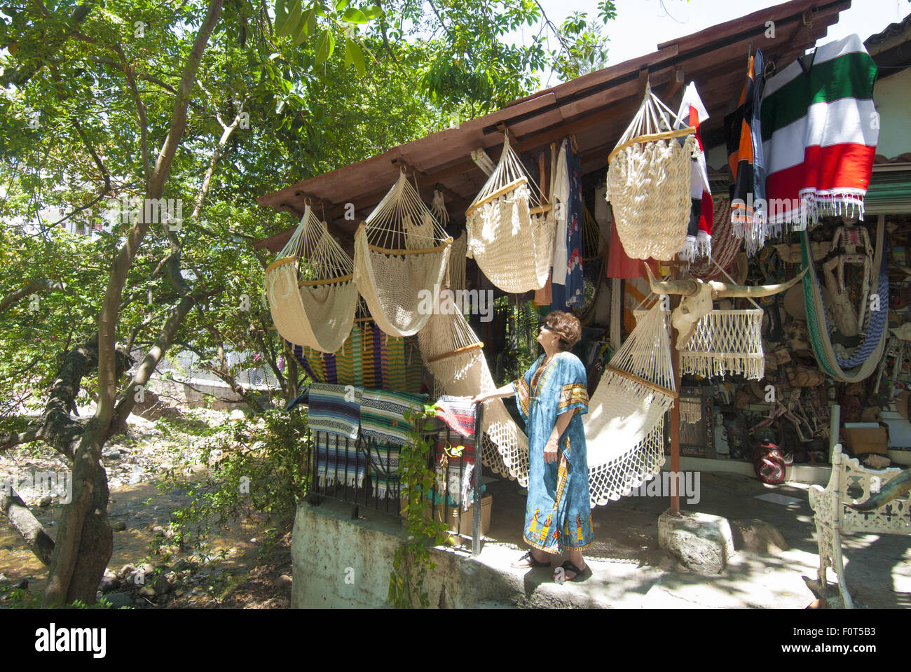 Donna shopper ispeziona amache in un negozio sul fiume Cuale Island, un vivace mercato posto a Puerto Vallarta, Messico. Foto Stock