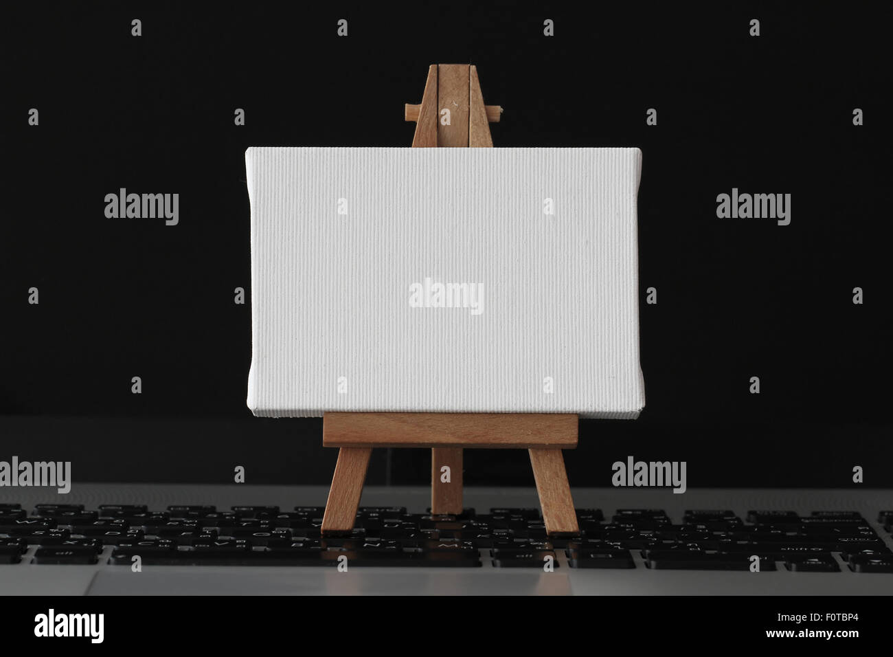 Tela vuota e il cavalletto in legno sul computer portatile come concetto Foto Stock