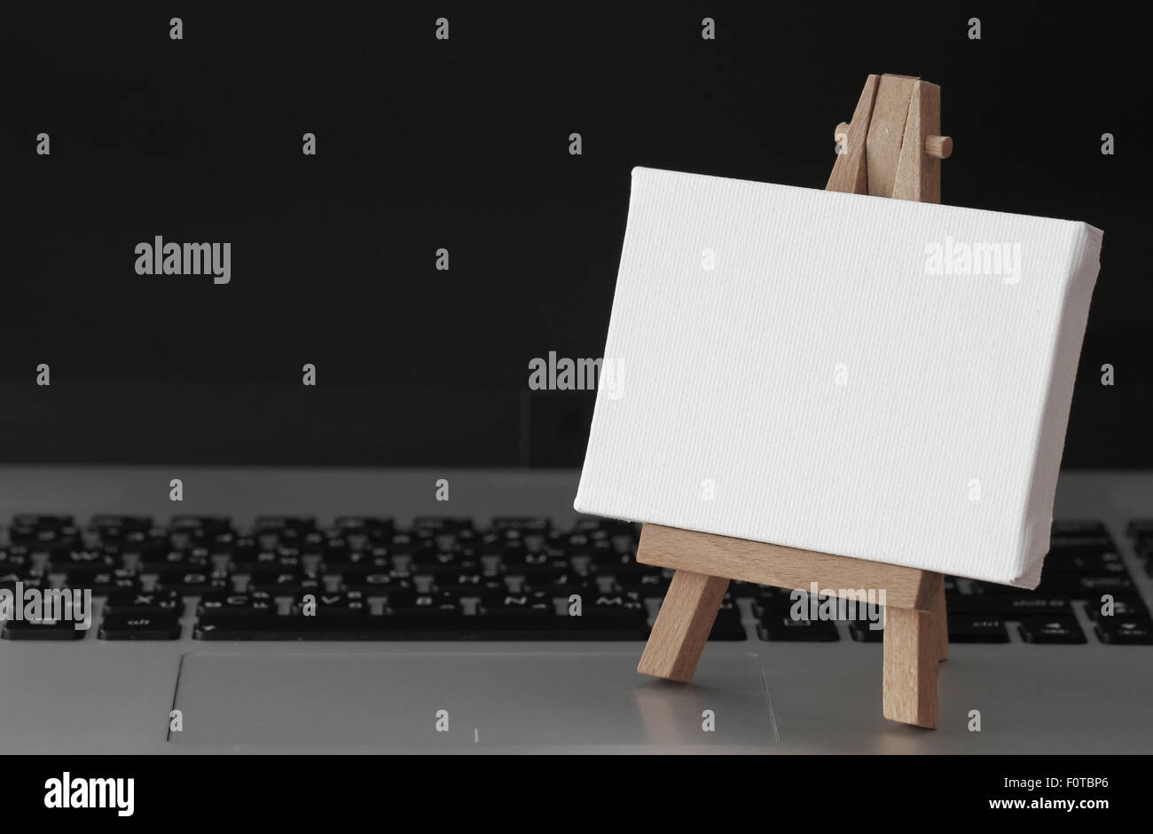 Tela vuota e il cavalletto in legno sul computer portatile come concetto Foto Stock