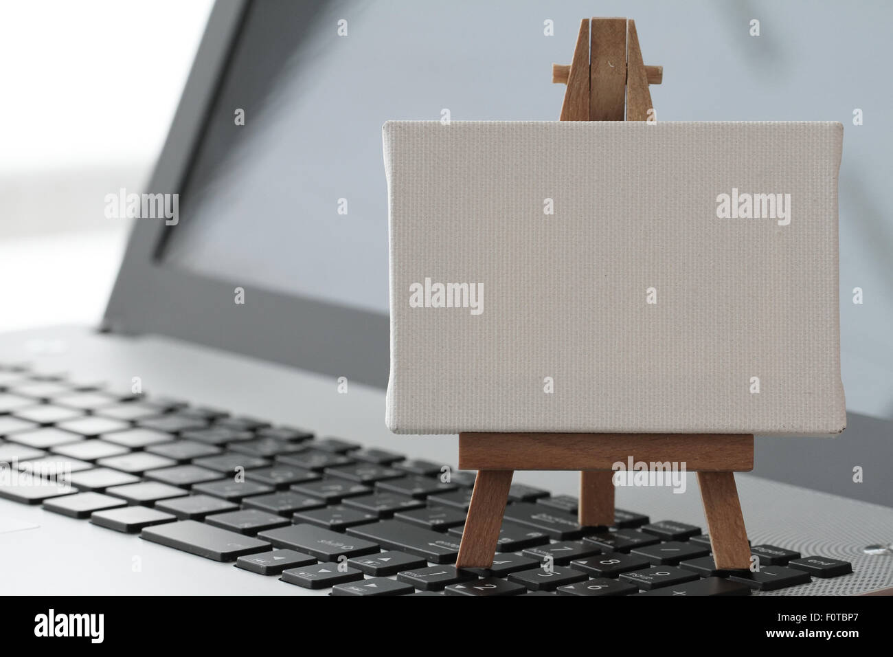 Tela vuota e il cavalletto in legno sul computer portatile come concetto Foto Stock