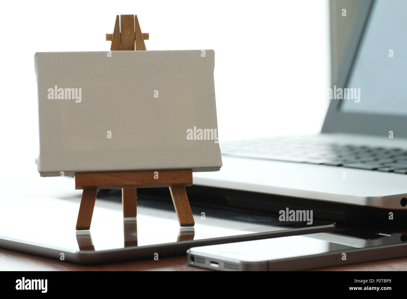 Tela vuota e il cavalletto in legno sul computer portatile come concetto Foto Stock