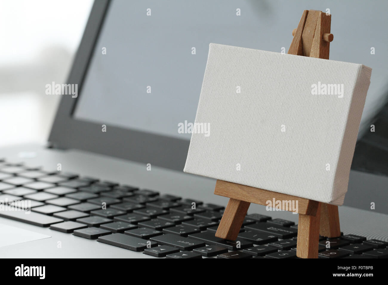 Tela vuota e il cavalletto in legno sul computer portatile come concetto Foto Stock