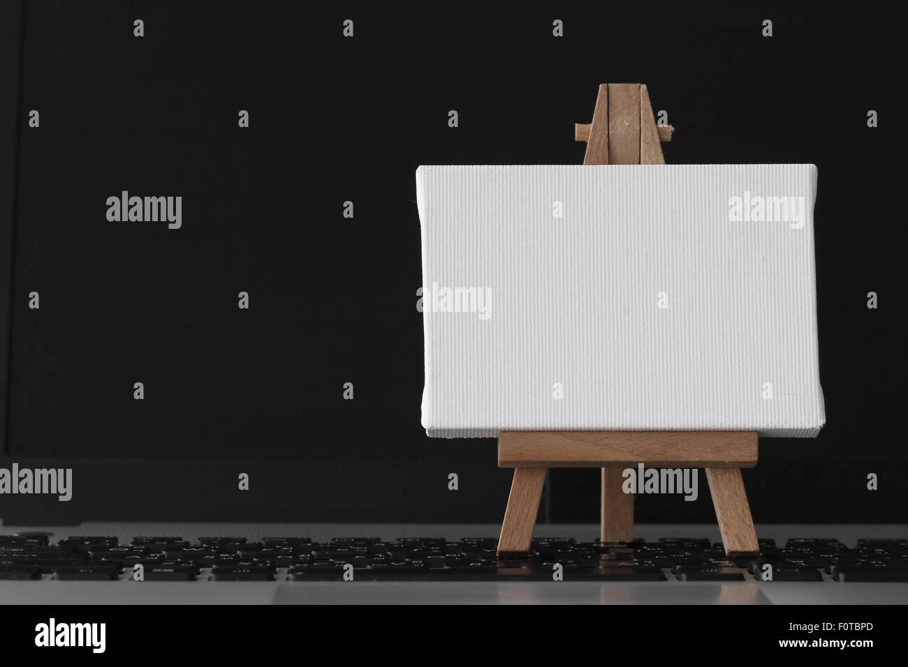 Tela vuota e il cavalletto in legno sul computer portatile come concetto Foto Stock
