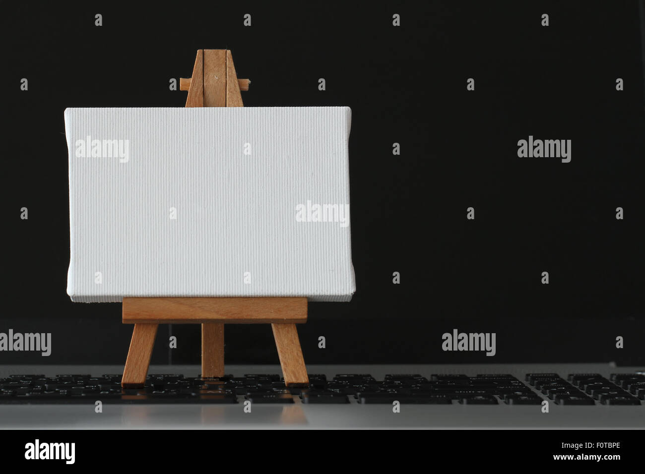 Tela vuota e il cavalletto in legno sul computer portatile come concetto Foto Stock