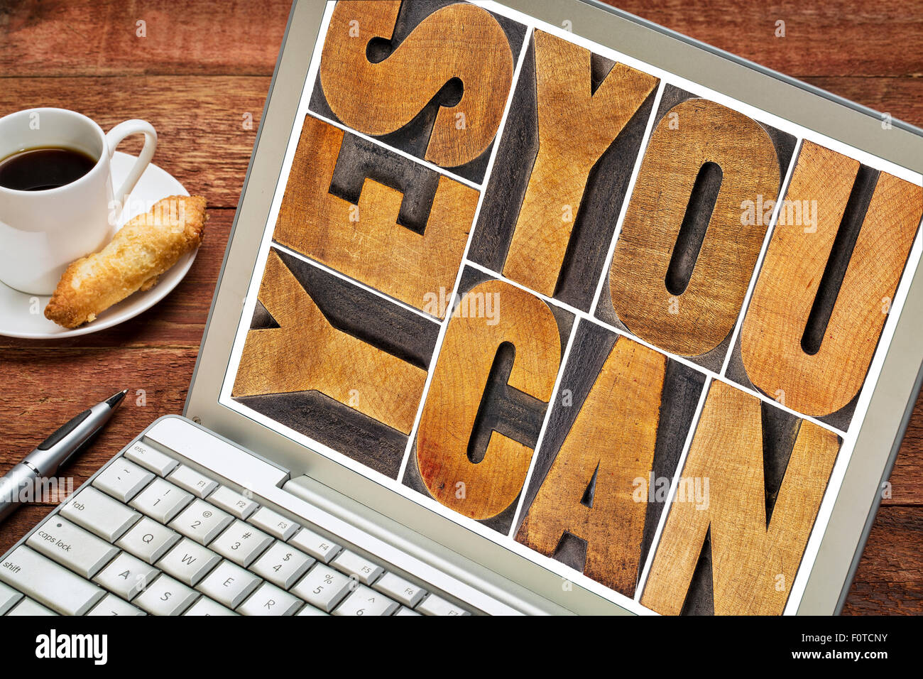 Sì è possibile - slogan motivazionale - un testo in rilievografia vintage tipo legno blocco di stampa su uno schermo di computer portatile con una tazza di COF Foto Stock