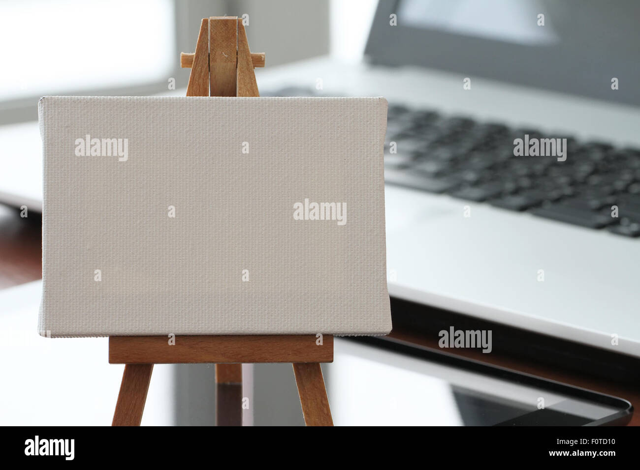 Tela vuota e il cavalletto in legno sul computer portatile come concetto Foto Stock