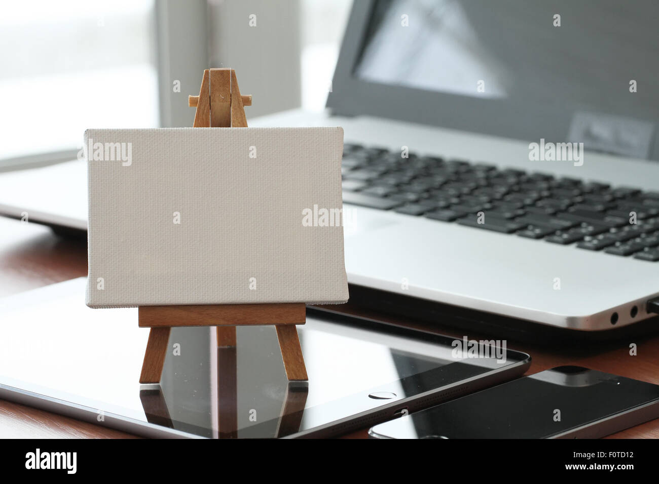Tela vuota e il cavalletto in legno sul computer portatile come concetto Foto Stock