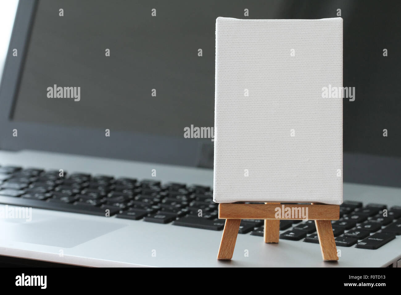 Tela vuota e il cavalletto in legno sul computer portatile come concetto Foto Stock