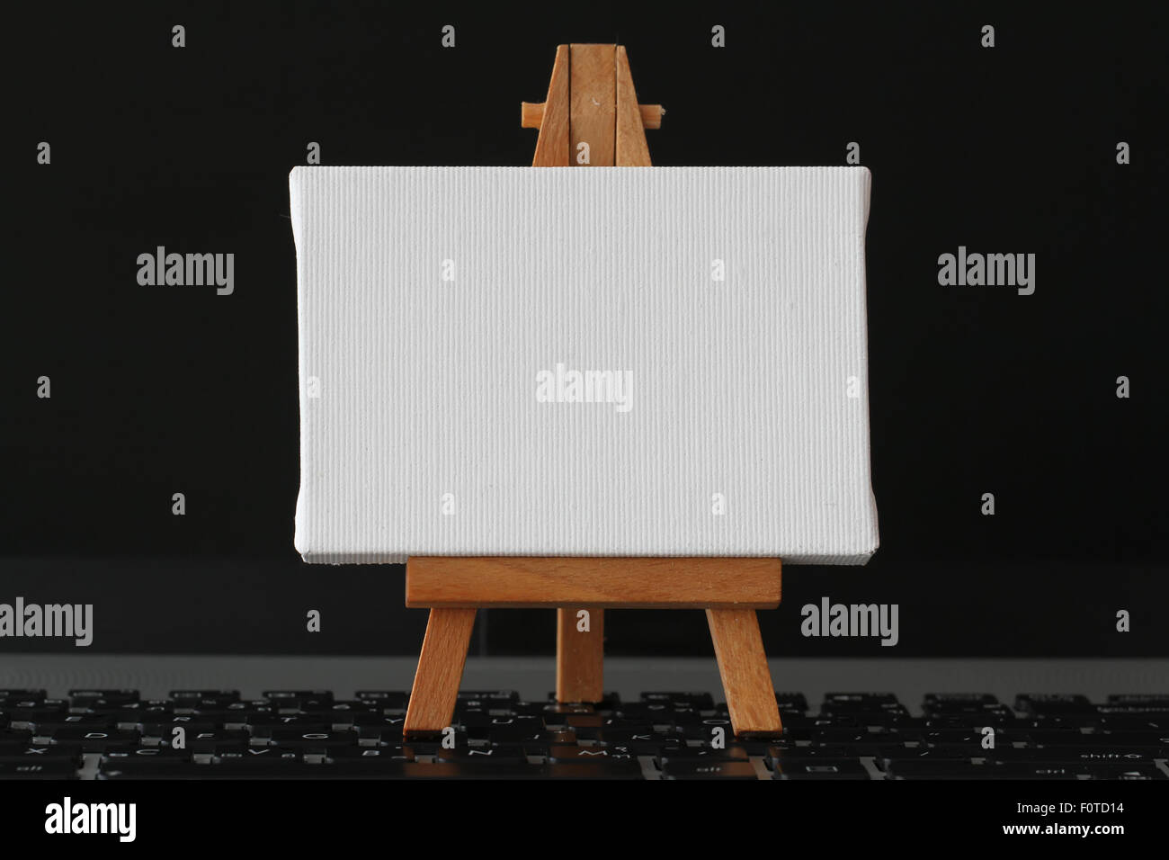 Tela vuota e il cavalletto in legno sul computer portatile come concetto Foto Stock