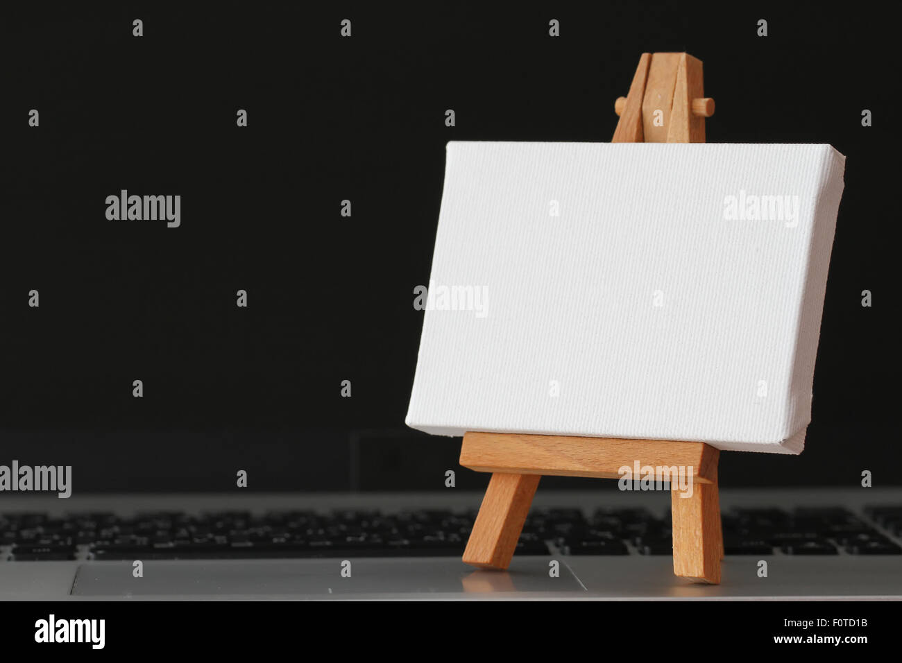 Tela vuota e il cavalletto in legno sul computer portatile come concetto Foto Stock
