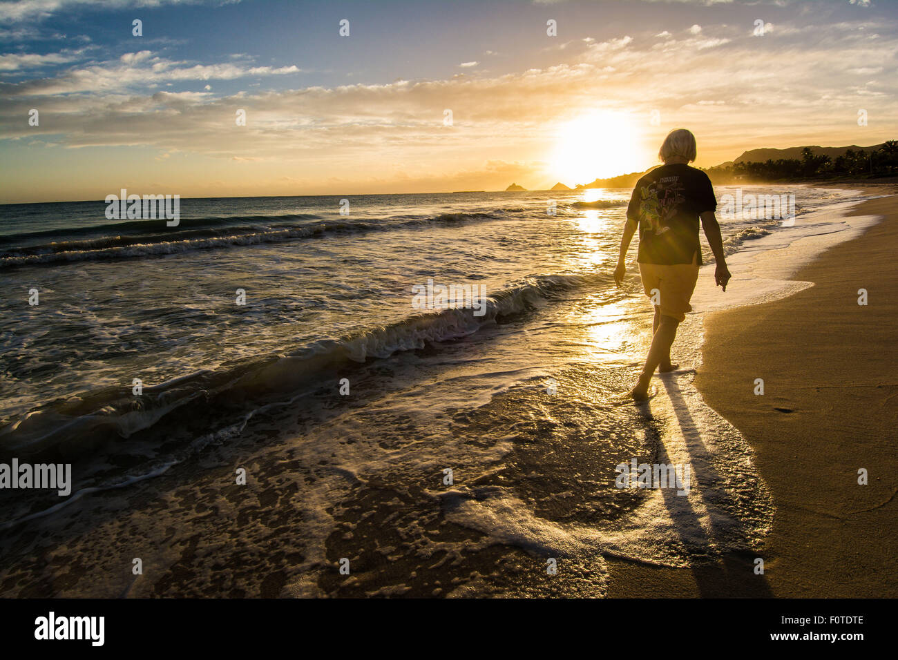 Donna di camminare sulla spiaggia al tramonto, Kailua, Oahu, Hawaii Foto Stock
