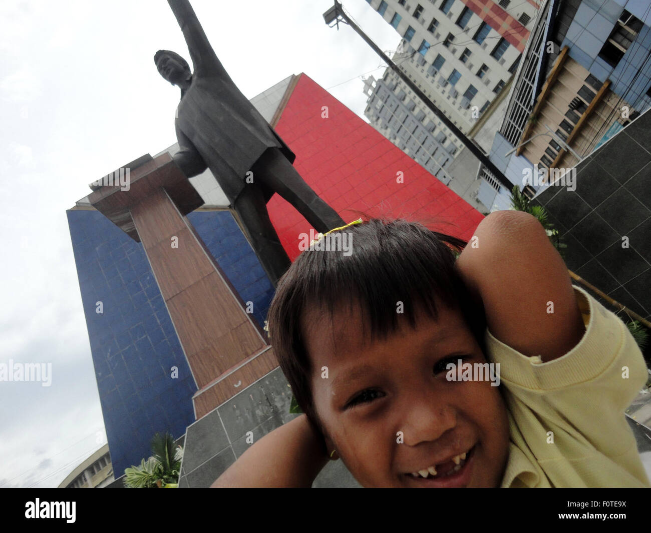Quezon City, Filippine. 21 Ago, 2015. Un bambino filippino photobombs davanti alla statua di ex senatore Benigno "" Ninoy Aquino Jr., padre del presidente filippino Benigno Aquino III, durante la XXXII anniversario di Ninoy Aquino di assassinio da parte di aggressori sconosciuti nella zona suburbana di Quezon City, a nord-est di Manila, Filippine. L'assassinio divenne la candela che infiamma una serie di proteste contro la tarda uomo forte Ferdinand Marcos. © Richard James Mendoza/Pacific Press/Alamy Live News Foto Stock
