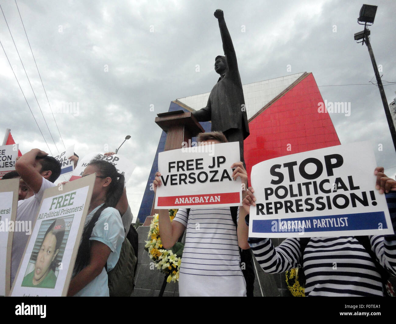 Quezon City, Filippine. 21 Ago, 2015. Andrea Rosal, figlia della fine del portavoce del partito comunista delle Filippine Gregorio "Ka Roger' Rosal, è mostrato in basso a sinistra, come attivisti visualizzare cartelloni davanti alla statua di ex senatore Benigno "" Ninoy Aquino Jr., padre dell'attuale presidente filippino Benigno Aquino III, durante un rally nella zona suburbana di Quezon City, Filippine, al trentaduesimo anniversario dell assassinio di Ninoy Aquino da ignoti assalitori. Credito: PACIFIC PRESS/Alamy Live News Foto Stock