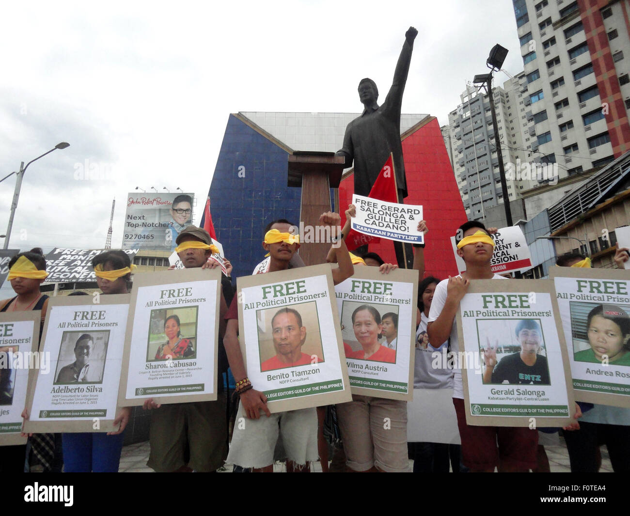 Quezon City, Filippine. 21 Ago, 2015. Gli attivisti indossando blindfolds giallo tenere cartelli contenenti i ritratti di presunti prigionieri politici nel paese, di fronte alla statua di ex senatore Benigno "" Ninoy Aquino Jr., padre dell'attuale presidente filippino Benigno Aquino III, durante un rally nella zona suburbana di Quezon City, Filippine, al trentaduesimo anniversario dell assassinio di Ninoy Aquino da ignoti assalitori. Credito: PACIFIC PRESS/Alamy Live News Foto Stock