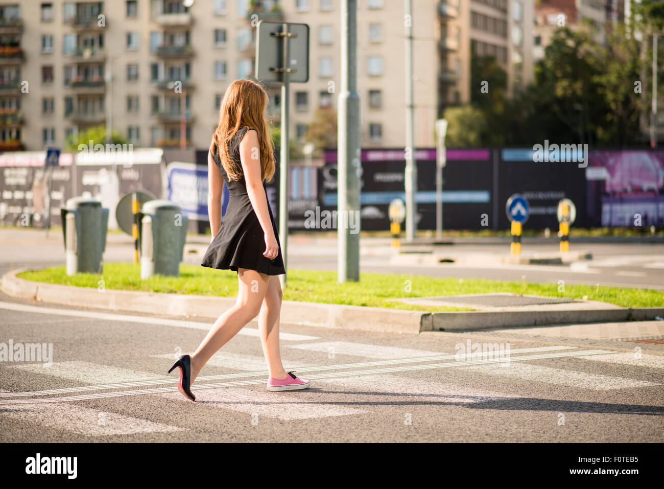Giovane donna walking street - un piede in sneaker e altri nel tacco alto scarpa Foto Stock