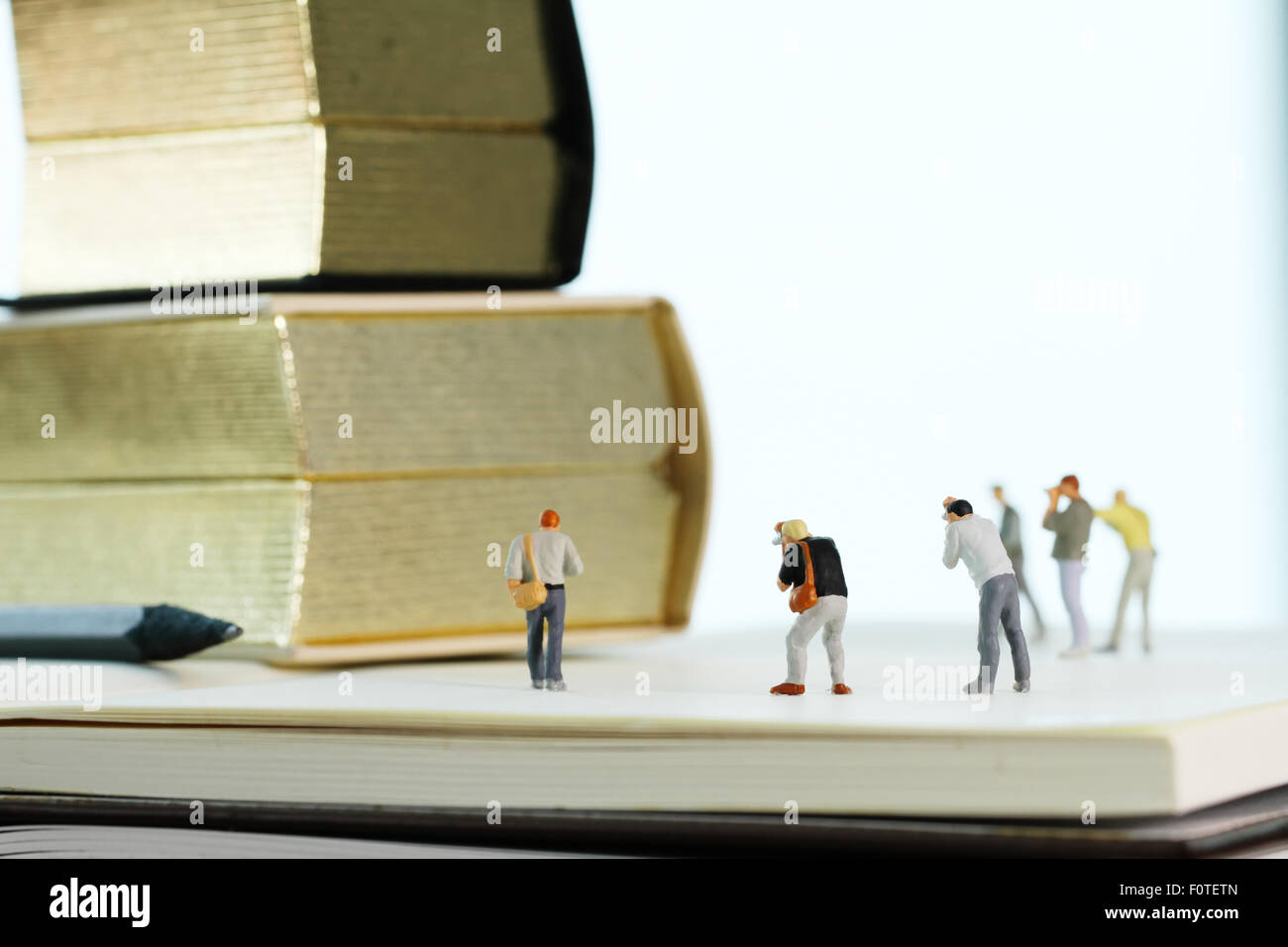 Idea creativa concetto - fotografo in miniatura con vintage golden book su aprire il notebook di carta Foto Stock