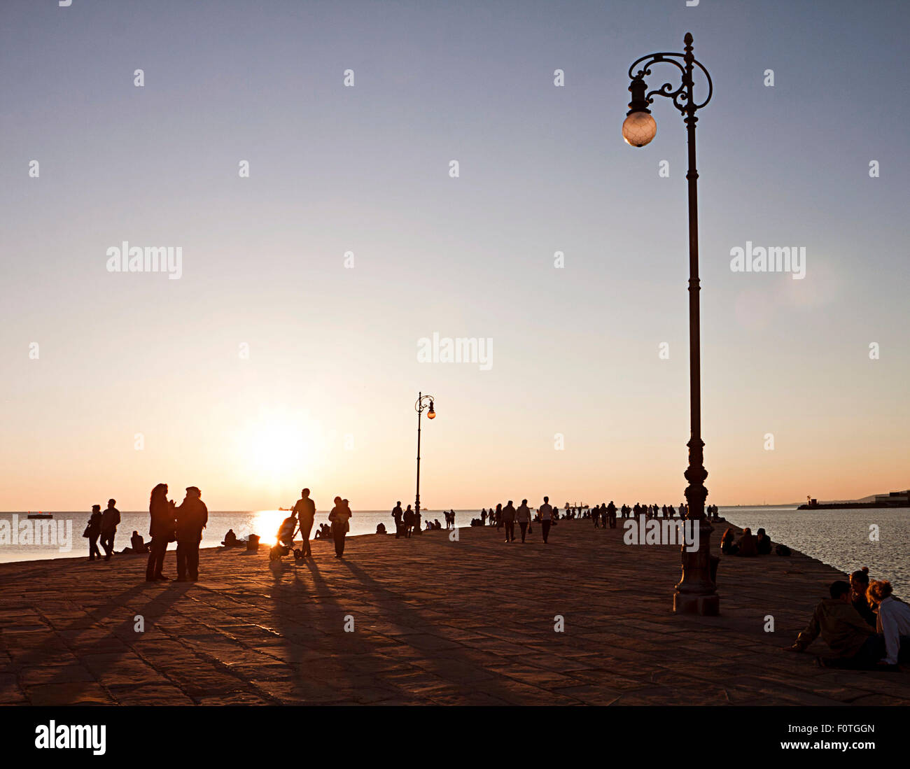 Trieste, Italia - la gente a fare una passeggiata sul Molo Audace molo di Trieste al tramonto. Foto Stock