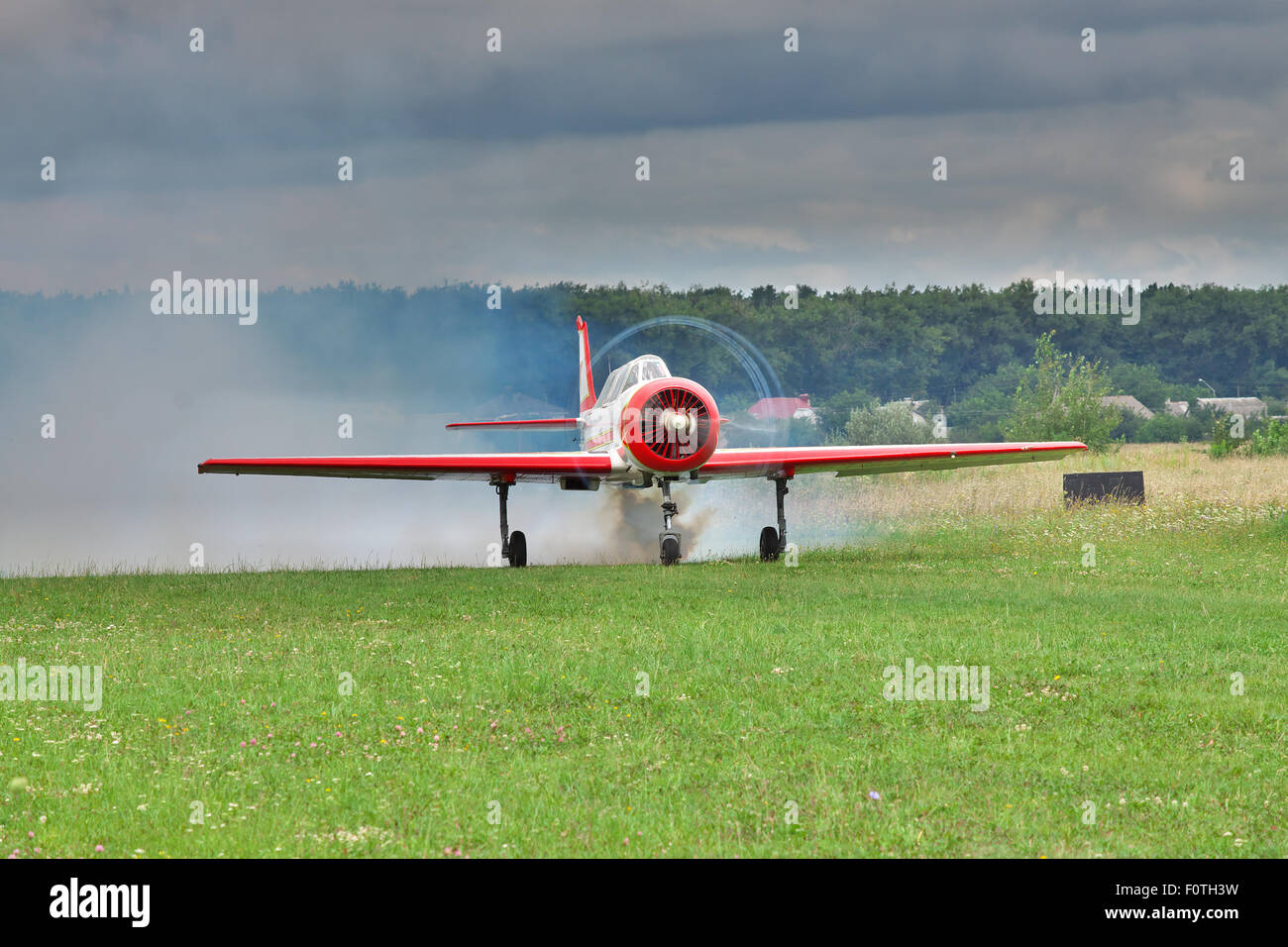 Velivolo acrobatico è tenuto spento con fumo dal suolo pista di atterraggio per aerei con cielo drammatico sullo sfondo Foto Stock