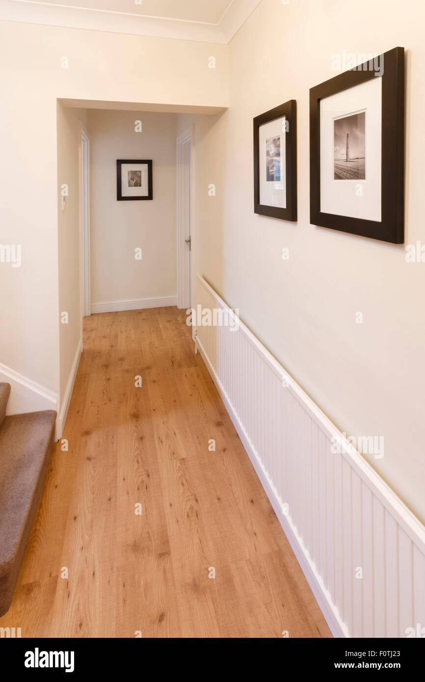 Corridoio in una casa con il pavimento in legno e le immagini sulla parete Foto Stock