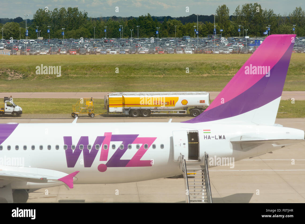 Piano Wizzair.com sul terreno all'Aeroporto di Luton con carburante Shell tanker in background a Luton, Bedfordshire, Inghilterra Foto Stock