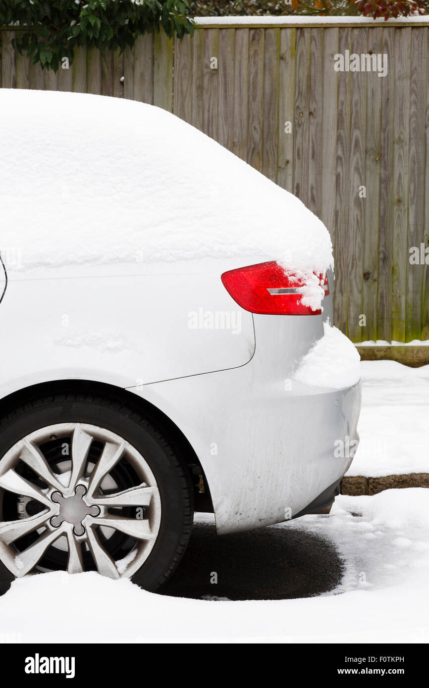 Lato della macchina coperto di neve parcheggiato su una strada britannico in inverno Foto Stock