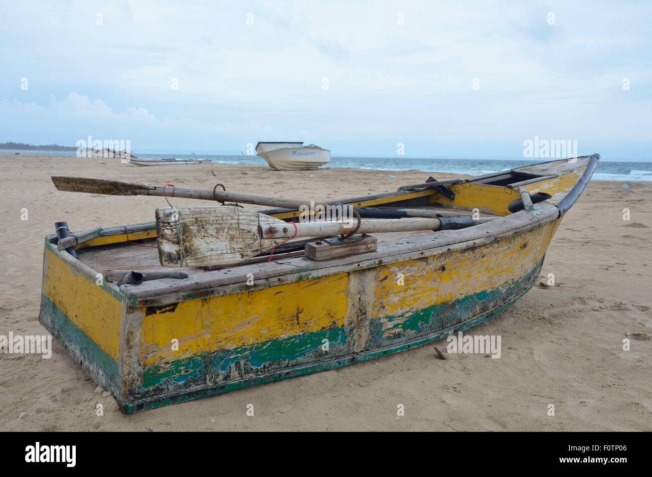 Questo vecchio, unsafe barca da pesca che giace sulla spiaggia di Inhambane, il Mozambico è in uso quotidiano. Foto Stock
