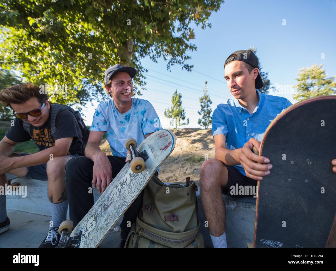 Giovani uomini con skateboard in chat in posizione di parcheggio Foto Stock