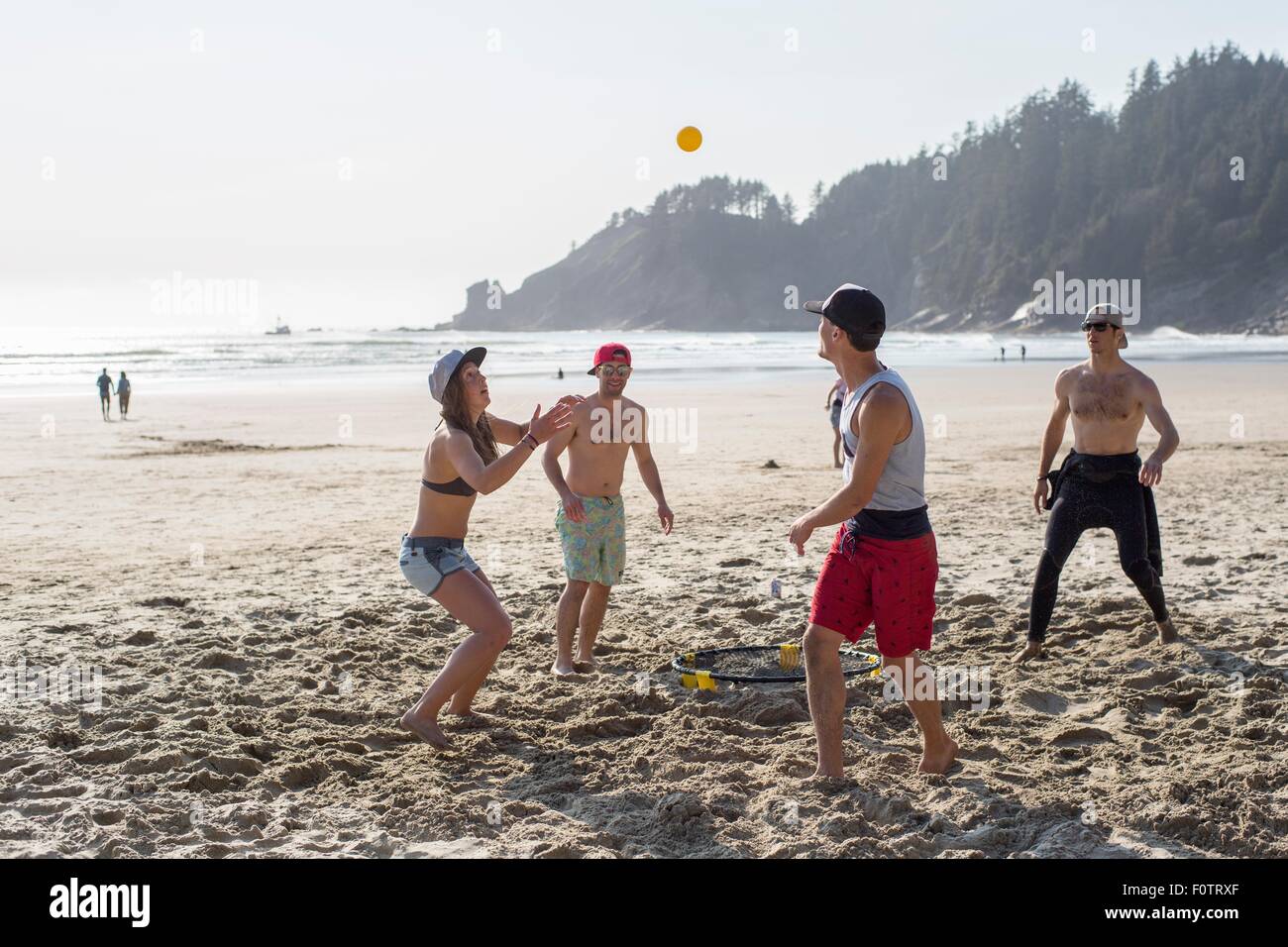 Quattro amici adulti giocando con la palla sul breve Sands Beach, Oregon, Stati Uniti d'America Foto Stock