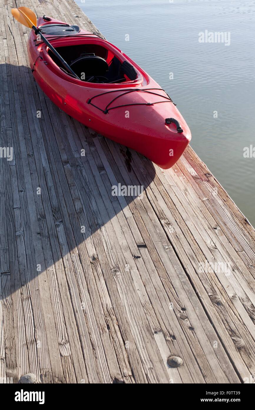 Elevato angolo di visione del kayak e pagaia sul molo di legno accanto all'acqua Foto Stock