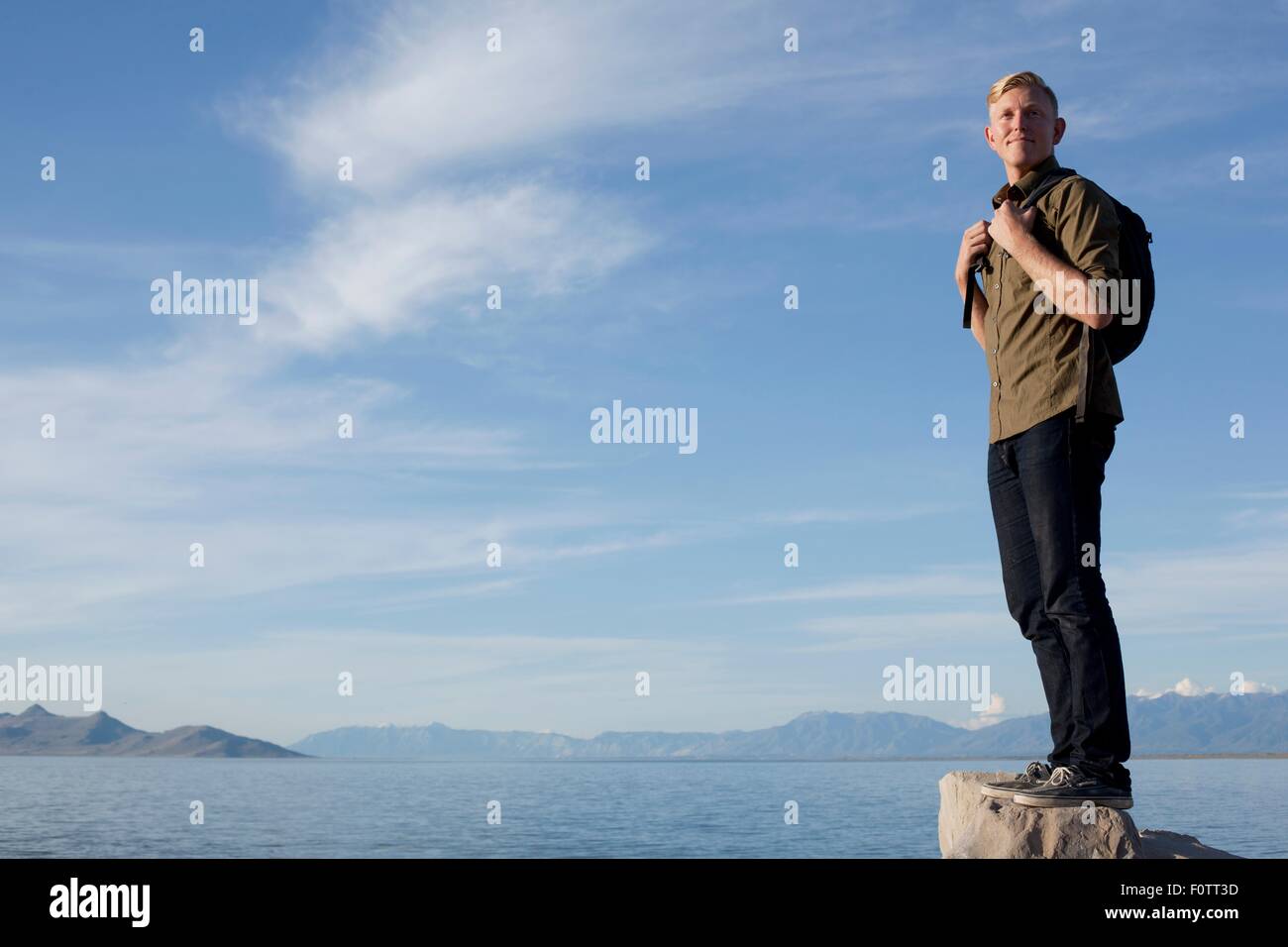 Giovane uomo che indossa uno zaino in piedi sulla roccia che guarda lontano, fantastica Salt Lake, Utah, Stati Uniti d'America Foto Stock