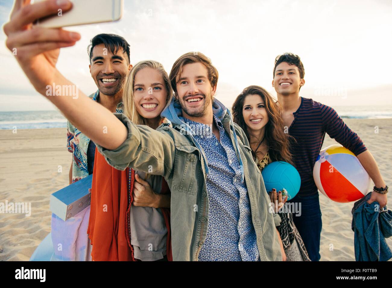 Gruppo di amici sulla spiaggia, tenendo autoritratto con lo smartphone Foto Stock