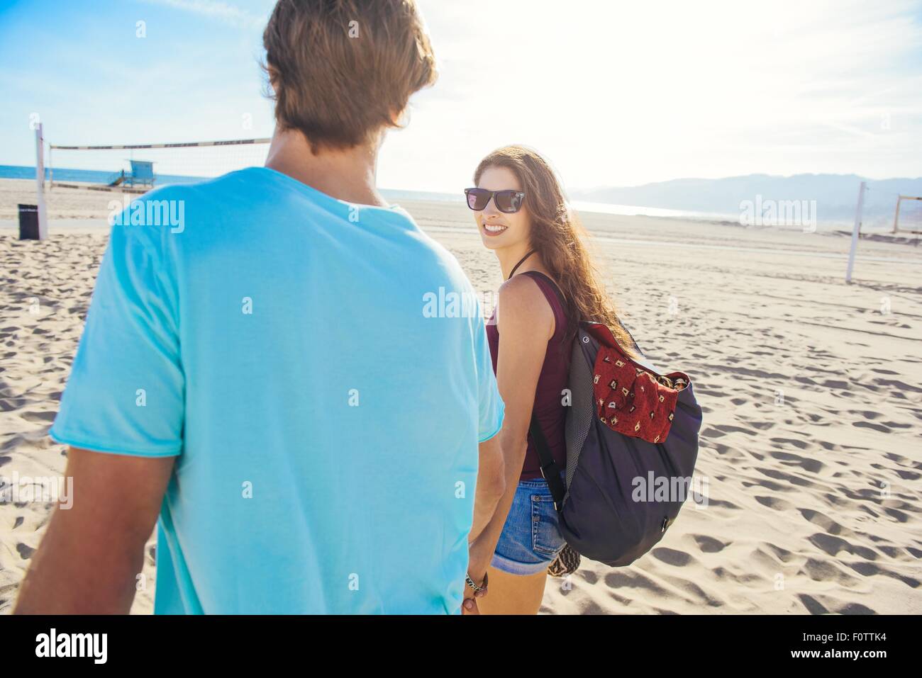 Coppia giovane camminando sulla spiaggia, vista posteriore Foto Stock