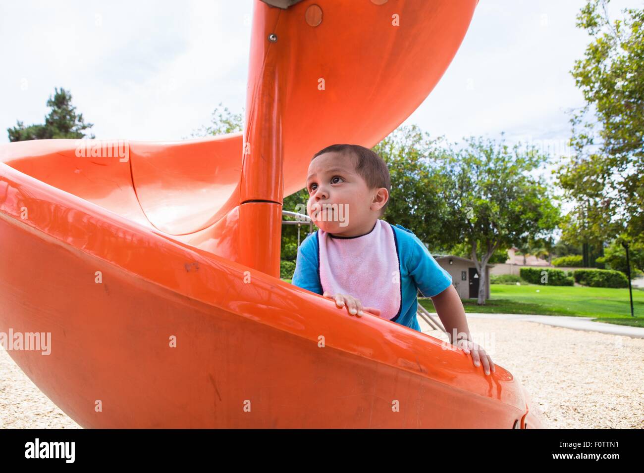 Maschio arrampicata toddler arancione parco giochi slitta Foto Stock