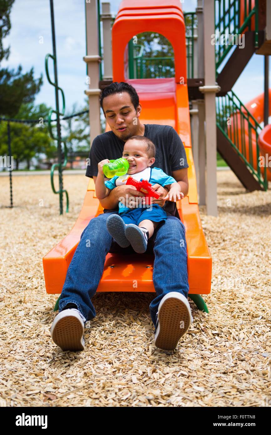 Giovane con toddler fratello sul parco giochi slitta Foto Stock