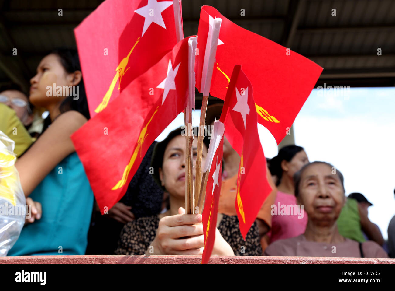 Yangon, Myanmar. 21 Ago, 2015. Una donna trattiene il Myanmar la Lega nazionale per la democrazia (NLD) partito flags come ella attende di ascoltare un discorso del leader del partito di opposizione NLD Aung San Suu Kyi durante un elettore campagna di educazione nella periferia di Yangon, Myanmar, Agosto 21, 2015. Credito: U Aung/Xinhua/Alamy Live News Foto Stock