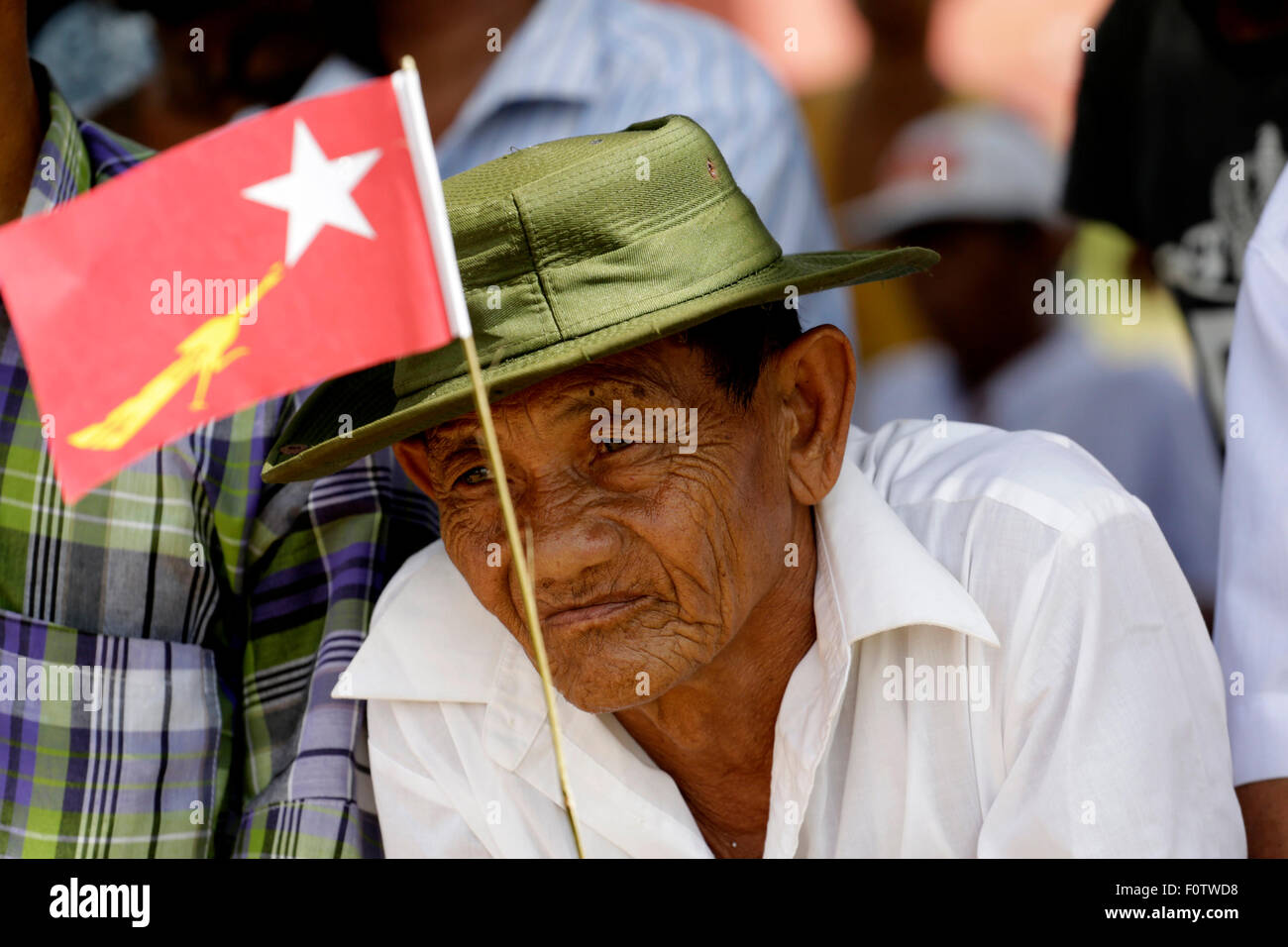 Yangon, Myanmar. 21 Ago, 2015. Un uomo detiene un Myanmar la Lega nazionale per la democrazia (NLD) partito bandiera come egli attende di ascoltare un discorso del leader del partito di opposizione NLD Aung San Suu Kyi durante un elettore campagna di educazione nella periferia di Yangon, Myanmar, Agosto 21, 2015. Credito: U Aung/Xinhua/Alamy Live News Foto Stock