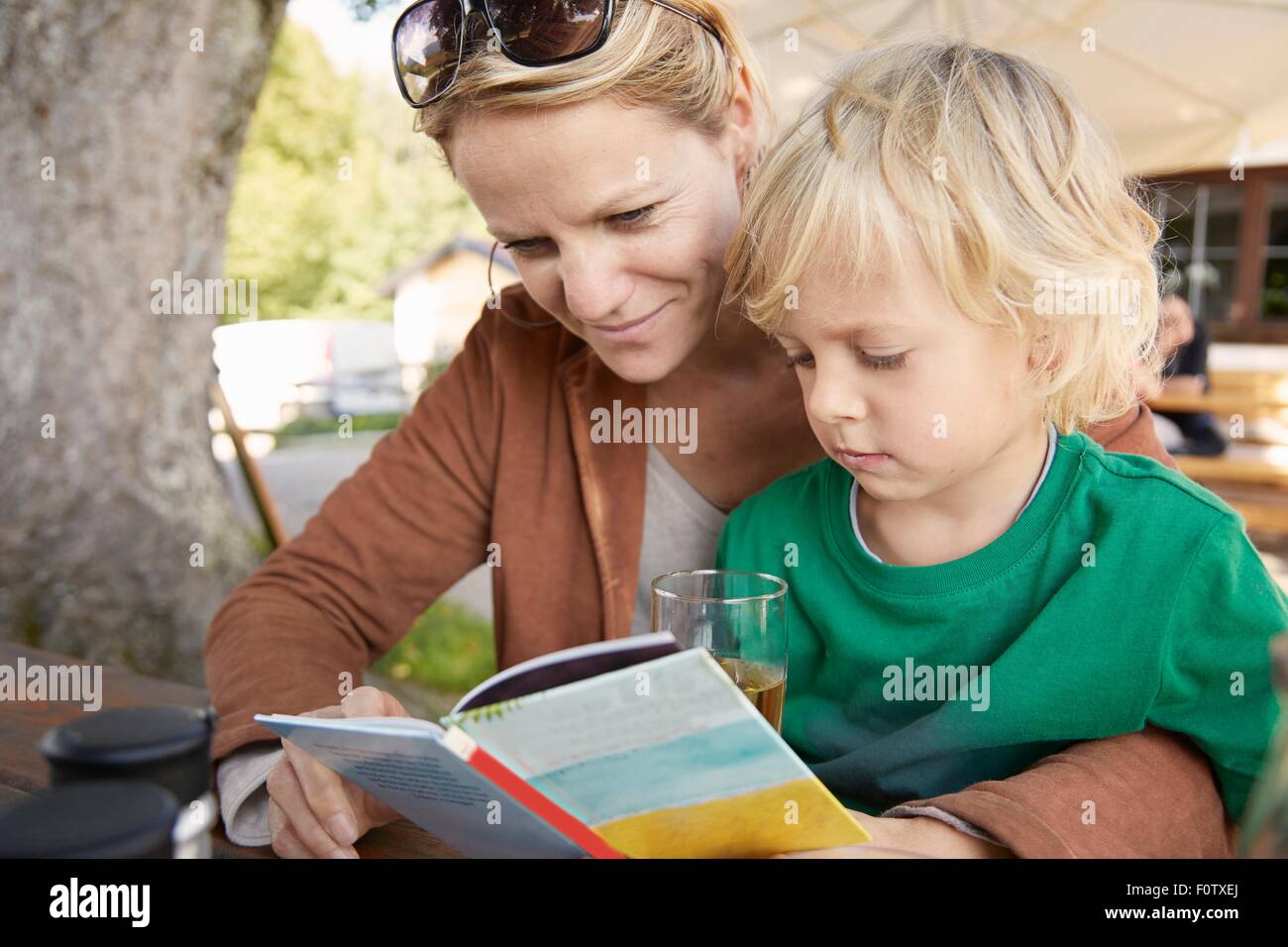 Madre e figlio lettura libro insieme all'aperto Foto Stock