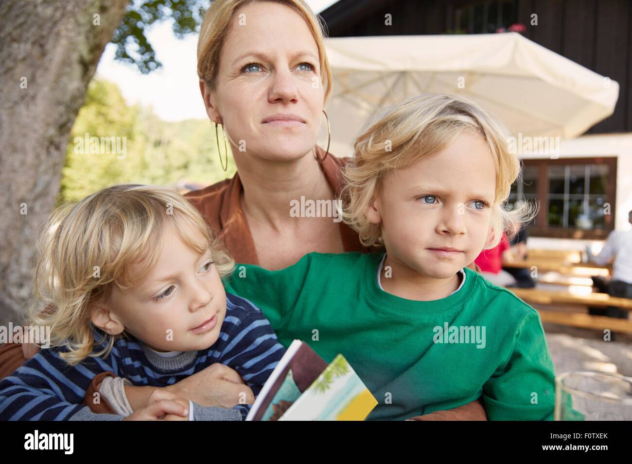 Madre e due figli seduti insieme, all'aperto Foto Stock