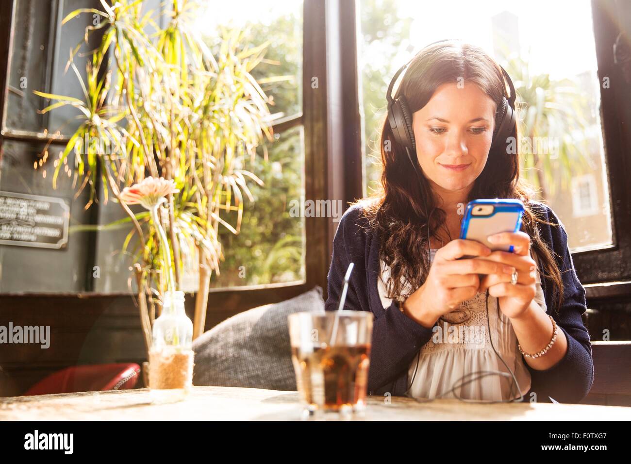 Metà donna adulta che indossa gli auricolari utilizza lo smartphone Foto Stock